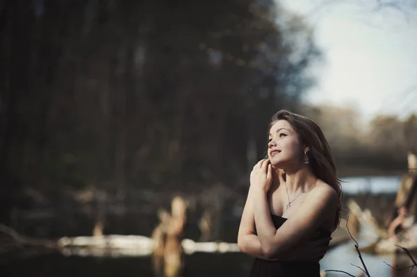 Bruna ragazza sta vicino all'albero vicino all'acqua — Foto Stock