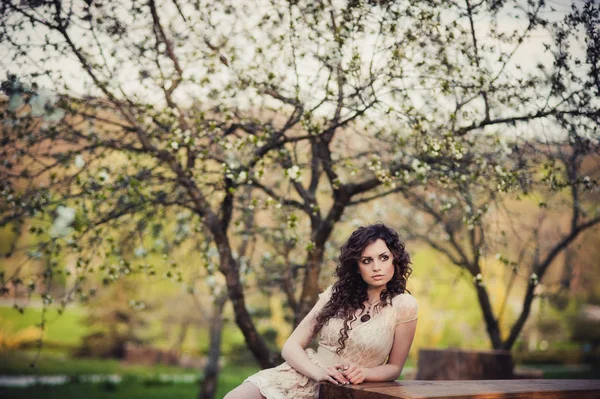 Curly brunette meisje permanent in bloeiende bomen — Stockfoto