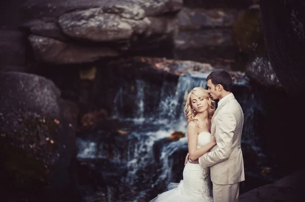 Couple de mariage en robes blanches à la cascade — Photo