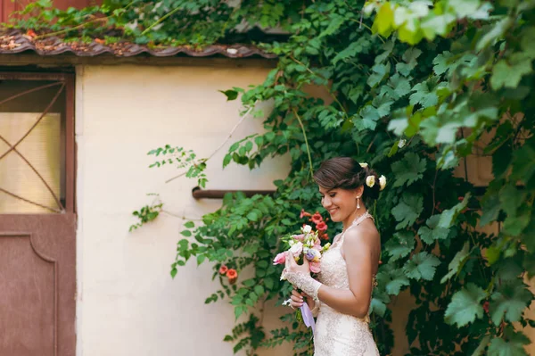 Brunette bride at the wall with weaving leaves — Stock Photo, Image