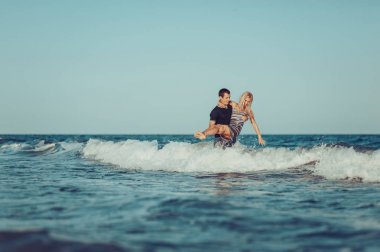 Genç aşık bir çift sahilde yürüyor.