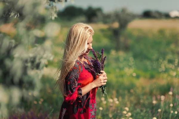 Блондинка в красном платье на природе — стоковое фото