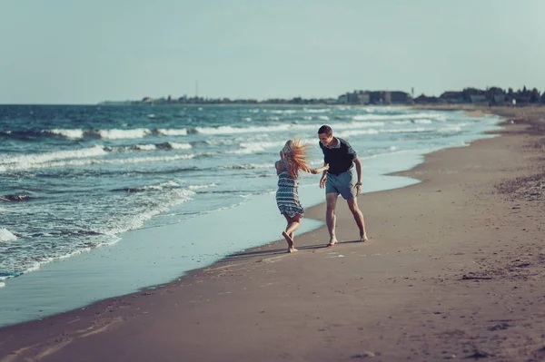 Mladý pár v lásce chůze na pláži — Stock fotografie