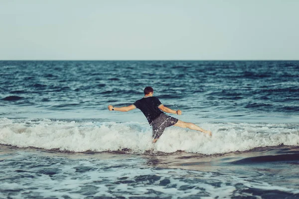 Un joven está saltando y divirtiéndose en el mar —  Fotos de Stock