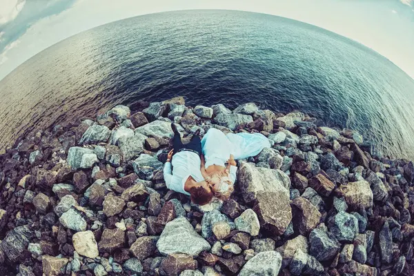 Una pareja de enamorados yace sobre piedras cerca del mar — Foto de Stock