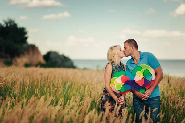 Líbání pár ve vysoké trávě s hračkou větrný mlýn — Stock fotografie