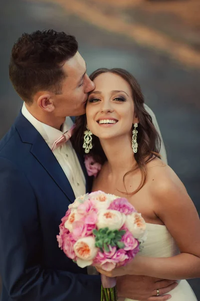 Schöne Braut und Bräutigam umarmen und küssen sich am Hochzeitstag — Stockfoto