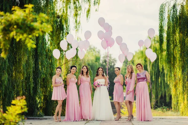 Bruden med tärnor i rosa klänningar för en promenad — Stockfoto