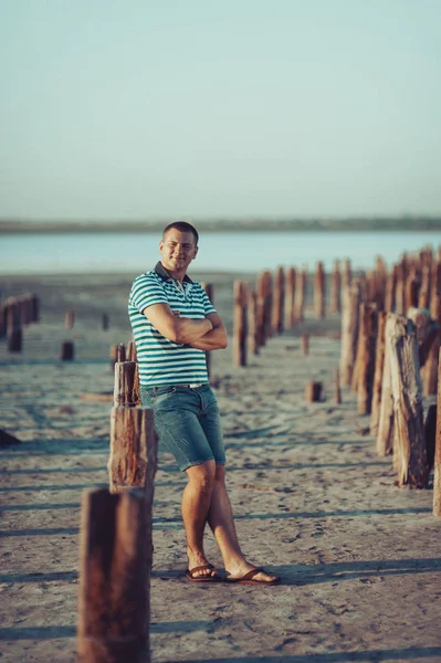 El tipo en pantalones cortos y una camiseta está de pie cerca de los postes en el es — Foto de Stock