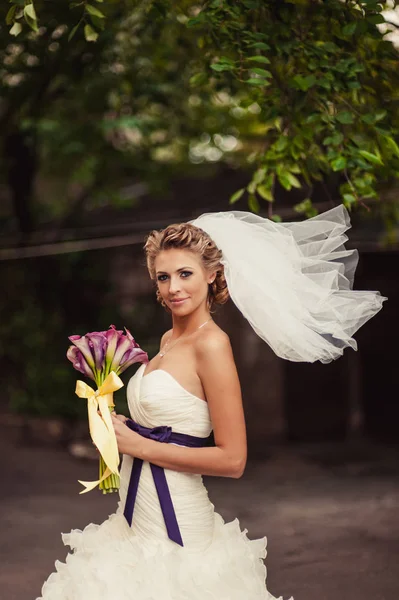 Schöne Braut mit einem Strauß lila Callas — Stockfoto