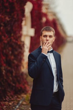 Kırmızı yaprakları ile bir duvarının yakınında bir yolda damat