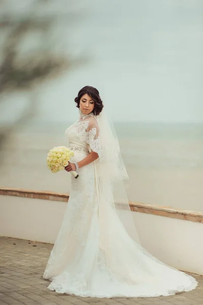 Beautiful brunette bride on a promenade on the waterfront — Stock Photo, Image