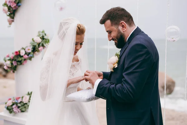 Braut und Bräutigam tragen Ringe bei einer Zeremonie am Meer — Stockfoto