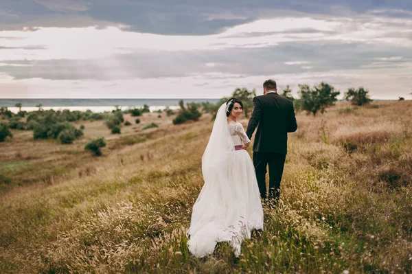 Noivo e noiva em um passeio ao ar livre perto da água — Fotografia de Stock