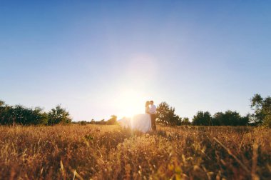 Gelin ve damat birlikte denize yakın gün batımında yürüyor