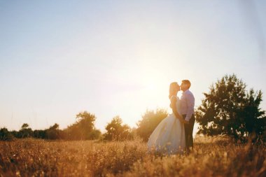 Gelin ve damat birlikte denize yakın gün batımında yürüyor
