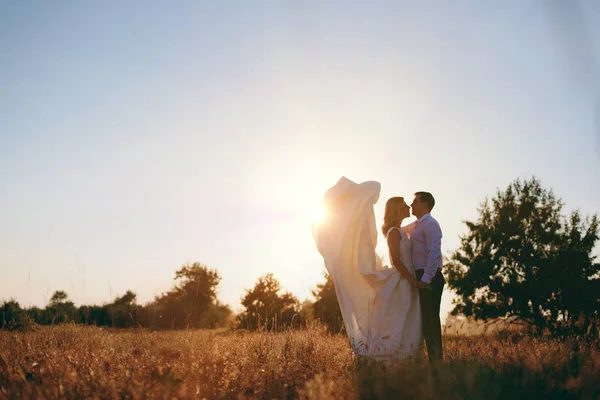 Gelin ve damat birlikte denize yakın gün batımında yürüyor — Stok fotoğraf