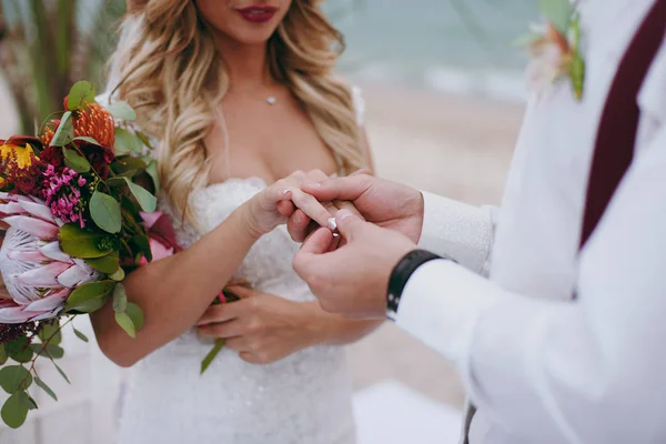 Mano del novio poniendo un anillo de bodas en el dedo de la novia —  Fotos de Stock