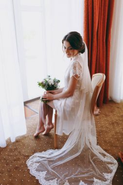 Gelin esmer peçe ve beyaz saten sabahlık pencerenin kenarında oturur