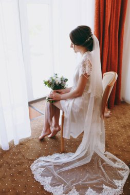 Gelin esmer peçe ve beyaz saten sabahlık pencerenin kenarında oturur
