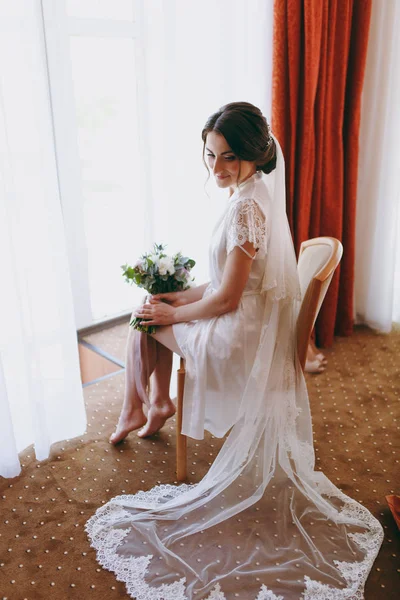 Gelin esmer peçe ve beyaz saten sabahlık pencerenin kenarında oturur