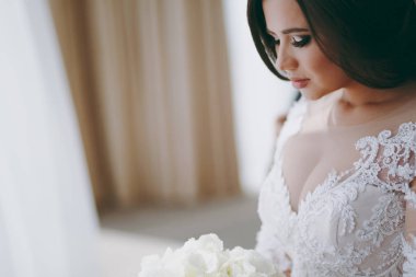 Bir gelinlik güzel gelin pencerenin yanındaki sandalyeye oturur