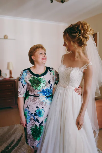 Νύφη στο γάμο φόρεμα στέκεται με μητέρα στο σπίτι το πρωί — Φωτογραφία Αρχείου