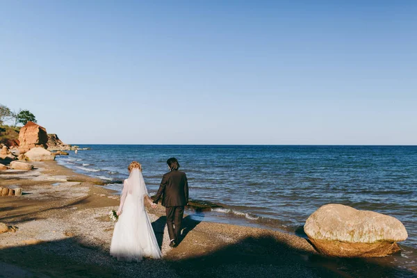 Bruid en bruidegom op een wandeling buiten op de zee — Stockfoto