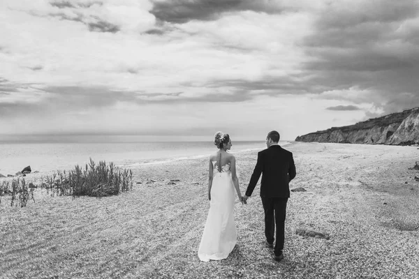 Brudgummen och bruden på en promenad utomhus vid havet — Stockfoto