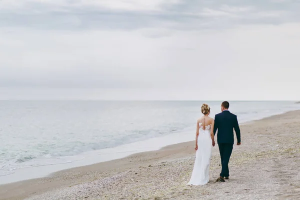 Brudgummen och bruden på en promenad utomhus vid havet — Stockfoto