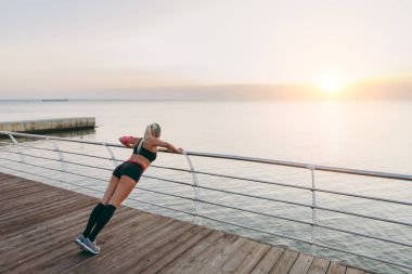 Müzik ve güneş doğarken deniz eğitim Kulaklığımda uzun sarı saçlı genç güzel atletik kız