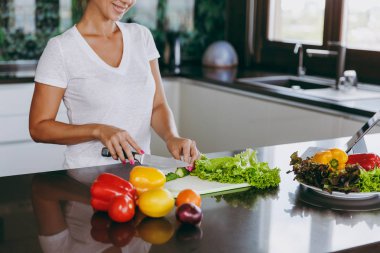 Genç bir kadın sebze mutfakta bıçakla keser. Sağlıklı gıda - sebze salatası. Diyet kavramı. Sağlıklı bir yaşam tarzı. Evde yemek. Yemek hazırlamak kadar yakın