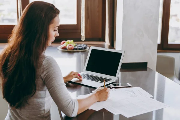 Молодая современная деловая женщина работает с документами и ноутбуком в — стоковое фото