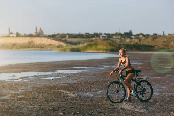 Uma mulher loira forte em um terno colorido senta-se em uma bicicleta em um — Fotografia de Stock