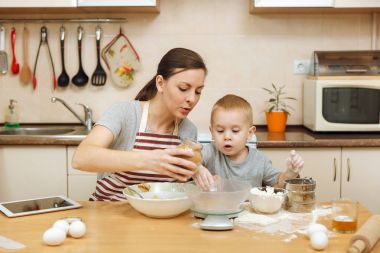 Küçük çocuk çocuk anne Noel masanın üzerine tablet ile ışık mutfakta zencefilli bisküvi pişirmek için yardımcı olur. Mutlu aile anne 30-35 yıl ve çocuk 2-3 hafta sonu sabah evde. İlişki kavramı