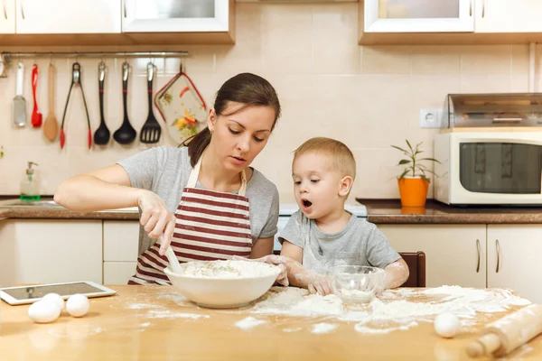 Jongen-jongetje helpt moeder om te koken kerst gember koekje in lichte keuken met tablet op tafel. Gelukkige familie moeder 30-35 jaar en kind 2-3 in weekend's ochtends thuis. Begrip van de relatie — Stockfoto