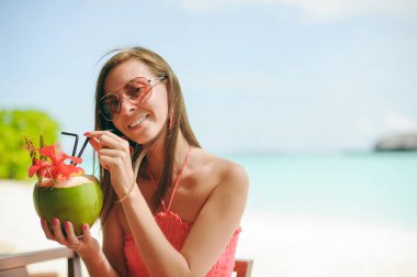 Maldivler sahilde bir pembe çiçek ile süslü masada yeşil Hindistan cevizi lezzetli kokteyl