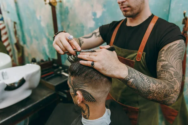 Крупним планом чоловік стає модною стрижкою в перукарні. Чоловічий перукар в татуюваннях, що обслуговують клієнта . — стокове фото
