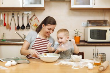 Küçük çocuk çocuk anne Noel masanın üzerine tablet ile ışık mutfakta zencefilli bisküvi pişirmek için yardımcı olur. Mutlu aile anne 30-35 yıl ve çocuk 2-3 hafta sonu sabah evde. İlişki kavramı