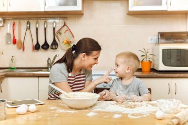 Küçük çocuk çocuk anne Noel masanın üzerine tablet ile ışık mutfakta zencefilli bisküvi pişirmek için yardımcı olur. Mutlu aile anne 30-35 yıl ve çocuk 2-3 hafta sonu sabah evde. İlişki kavramı