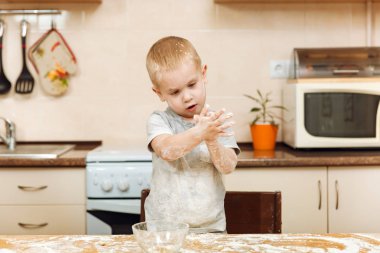 Küçük çocuk çocuk anne Noel ışık mutfakta zencefilli bisküvi pişirmek için yardımcı olur. Gri T-shirt hafta sonu sabah evde hamur ve un ile masada 2-3 yıl içinde mutlu sarışın çocuk.