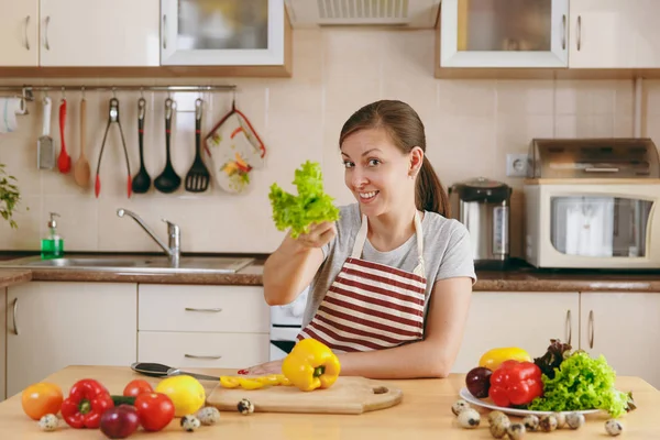 Молодая привлекательная женщина в фартуке с листьями салата на кухне. Концепция диеты. Здоровый образ жизни. Готовить дома. Готовьте еду. . — стоковое фото