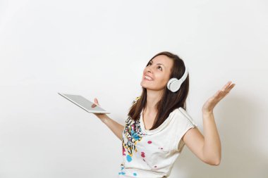 Güzel duygusal Avrupa kahverengi saçlı bir kadınla sağlıklı temiz cilt, büyüleyici smile, rahat hafif kıyafetler giymiş, dinler ve beyaz zemin üzerine tablet ile kulaklıklar müzik hoşlanır.