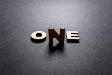 Ahşap harflerden birini siyah bir arka plan arka ışık ile karanlık bir doku üzerinde kelime. Aydınlatma etkisi.