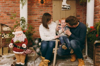 Küçük şirin bir çocuk çocuk ile mutlu anne Noel Baba evde dekore edilmiş yeni yıl odasında sandalye üzerinde oturan Kazak giymiş. Noel keyfi. Yaşam tarzı, Aile ve tatil 2018 kavramı