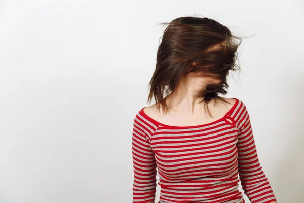 Schöne junge glückliche Frau mit braunen Haaren, in lässiger roter und grauer Kleidung, die lange gesunde saubere Haare vor weißem Hintergrund wedelt. Emotionen-Konzept. — Stockfoto