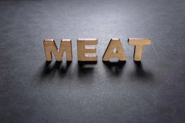 Λέξη κρέας ξύλινα γράμματα σε σκούρο υφή με ένα μαύρο φόντο με οπίσθιο φωτισμό. Εφέ φωτισμού. — Φωτογραφία Αρχείου