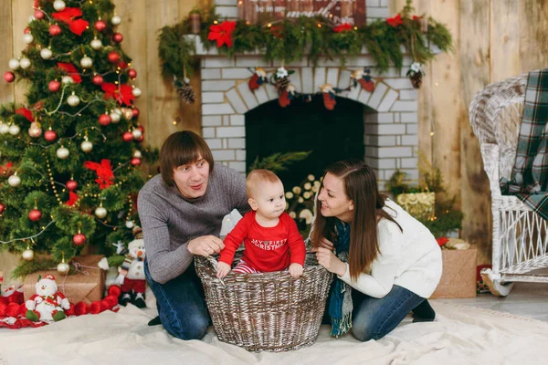 Retrato de padres felices juguetones jóvenes con un niño pequeño y lindo en una habitación decorada en casa. Navidad buen humor. Año Nuevo. Concepto de estilo de vida, familia y unión . — Foto de Stock