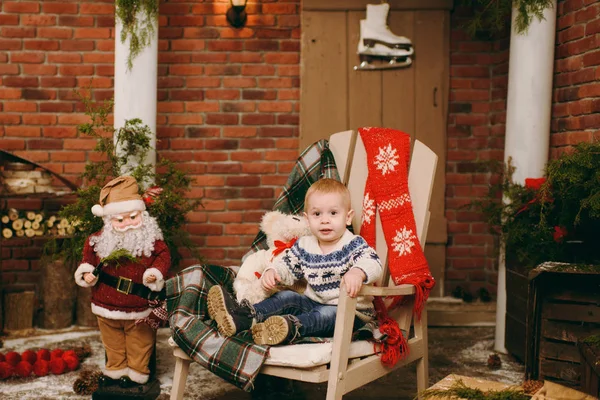 Juguetón niño lindo feliz vestido con suéter y vaqueros sentados en la silla con Santa en la habitación decorada de Año Nuevo en casa. Navidad buen humor. Estilo de vida, familia y vacaciones 2018 concepto — Foto de Stock