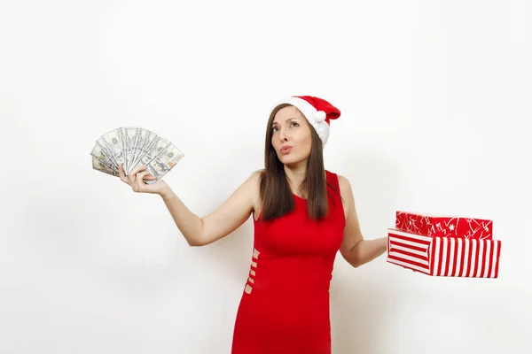 젊은 disconfused 빨간 드레스와 크리스마스 모자 흰색 배경에 선물 상자와 돈 지폐를 들고 좌절된 여자. 현재와 산타 소녀와 격리 하는 현금입니다. 새 해 휴일 2018 개념 — 스톡 사진